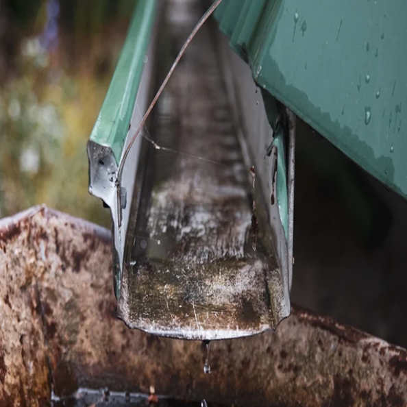 A gutter overflowing or dripping between seams is an early sign of roof-edge water damage.