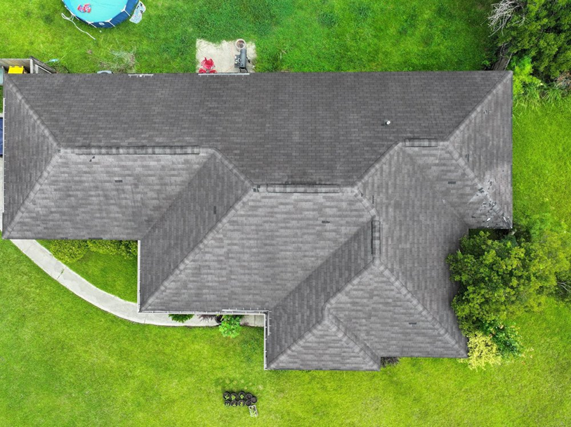 Exposed spots and displaced shingles on an aging roof, as seen in a drone inspection photo.